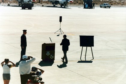 He walks to the podium where he makes a speech.  Chuck Yeager was the first man to exceed the speed of sound. He flew a rocket powered Bell X1 to do so.