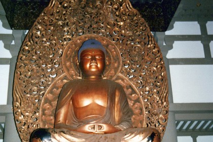 A statue of Bhudda sets majestically in the temple.  We have to take our shoes off to get him.