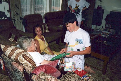 Grant opens a present for Granny while  Jenni looks on.