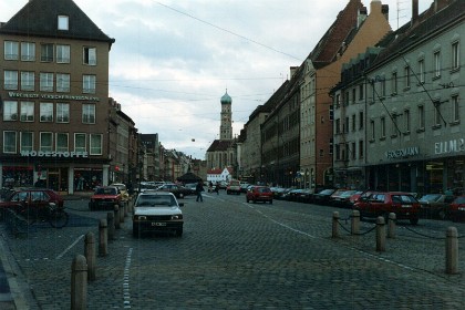 NCR Augsburg is still alive in 2022; it focuses on software and does not manufacture hardware any more. The Basilica of SS. Ulrich and Afra, a gothic Catholic church,  is in the distance on Maximilianstrasse.