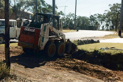 January 1990  &nbsp; A bobcat cleans the border back for us so that I can install a log retaining wall.