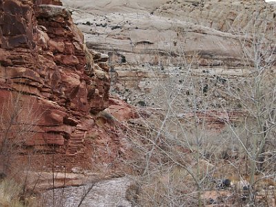 The Fremont River flows along the base of the structures  and SR24 follows the river for its length. Steps and a wall constructed from sandstone bricks are visible in the picture.