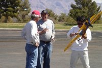 The Thunderbird at the 2006 VSC  On the final day, the wind blows like mad and half the field drops out. For some mad reason I fly and get through it. Here I'm on an adrenilin high reliving the flight with Lou Wolgast. Masaru is cleaning my plane for me.  Notice the bandage around my hand?