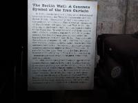 The sign says:    In 1961, Berlin became the focal point of increased tensions between the Western democracies and the Soviet Union. Dissatisfied with the economy and the political conditions in East Germany, thousands of East German refugees fled into West Berlin, the only gap in the Iron Curtain running from the Baltic to the Black Sea. To stop the exodus of their nation's elite, the East German government sealed the border between East and West Berlin. During the pre-dawn hours of Aug. 13, 1961, East German troops and workers, backed by Soviet tanks, ran barbed wire and built barricades. The wire soon gave way to heavy concrete segments topped with a concrete tube. A parallel barrier later went up in the East, leaving between them a brightly lit Todesstreifen (death strip), consisting of tank traps, fixed guns, attack dogs and land mines.  In 1989 communist governments collapsed across eastern Europe and on Nov. 9 the East German government partially opened the border in Berlin. A resulting flood of East Germans rushed to West Berlin, and following celebrations at the Brandenberg Gate and other locations, the Berlin Wall began to come down.  During the 28 years it separated East and West Berlin more than 5,000 people escaped over, through and under the wall. Approximately 100 people died making the attempt, most shot by border guards. : 2009-11-04 USA Air Force Museum