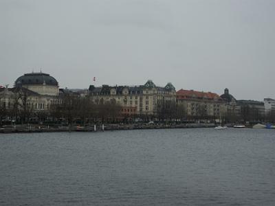 Wednesday 2009-03-25 &nbsp;&nbsp;Zurich Switzerland  We cross the Qualibrucke. Zurich Opera is the square-domed building on the left. The building flying the Swiss flag contains the Ambassador Hotel. Next to it is an apartment block that includes a theatre, restaurant and ballet school.