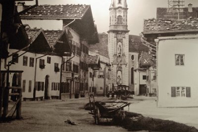 Sunday 20 June, 2010  I took this picture inside the museum of a photo from the early 1900's. The church has not changed, the Statue of Mathias Klotz is still there but the surrounding buildings have changed markedly. : 2010-06-20 mittenwald