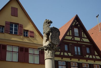 Wednesday 14 July, 2010 &nbsp;  The Dinkelsbühl coat of arms shows three ears of golden spelt  (Dinkel in Germanl) on three hills (bühl) from whence comes the town's name. Notice the opening for the hoist on the building at the left and a beam for the hoist on the building on the right. : 2010-07-13 Claus