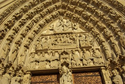 Friday 9 July, 2010 &nbsp;   This is the Portal of the Virgin situated on the left side of the west façade, built circa 1210-1220. It depicts the death of Mary, her ascension into Heaven and her coronation as Queen of the Heavens.  On the lower    lintel   , there are three prophets on the left and three Old Testament kings on the right, holding parchments showing that God’s promise has been fulfilled, Jesus has come to save humanity. Just above that, Mary lies on her death bed, surrounded by Jesus and the twelve Apostles. There are two angels at Mary’s head and feet, lifting up her shroud and taking her to Heaven. At the centre of the    tympanum   , Mary is in Heaven, seated on the same throne as Jesus. She is being crowned by an angel while Jesus blesses her and gives her her sceptre. She is made Queen of Heaven, Regina Cæli, in front of the Heavenly Court made up of angels, patriarchs, kings and prophets on the four successive    archivolts . : 2010-07-09 Paris2