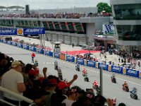 Sunday 13 October 2013 - Race day  The Moto2 riders have completed their warmup lap and reassemble on the grid. The start lights, hanging from the left side "Advance" sign, are off. : Sepang