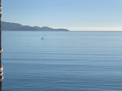 This is a long board being paddled upright in the calm waters of Cockle Bay.