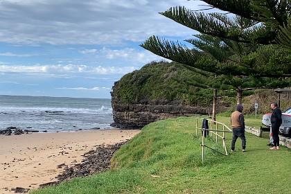 Tuesday 26 July 2022 The old bloke on the right is dressed in a wetsuit and holds his surf board.